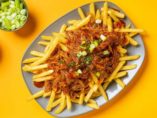 Frites croustillantes nappées d'une généreuse portion de pulled pork sauce barbecue, garnies de ciboule fraîche. Un délice !