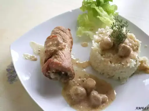 Délicieuse roulade de porc en sauce crémeuse, accompagnée d'une timbale de riz et d'une feuille de laitue.