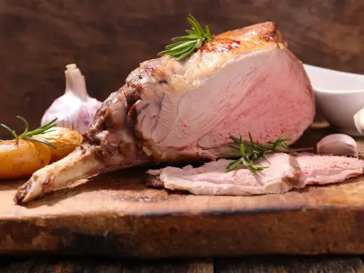 Un gigot d'agneau rôti, tendre et juteux, avec des pommes de terre et de l'ail. Ce gigot qui pleure de délice est prêt à être dégusté.