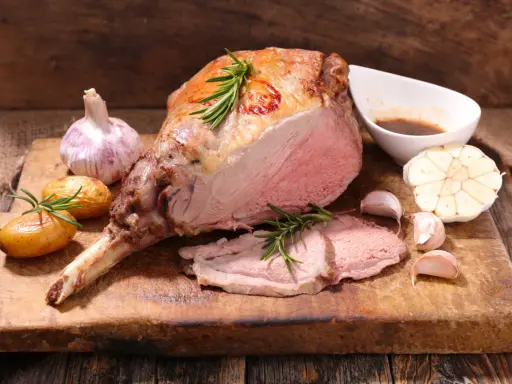 Gigot d'agneau rôti, tendre et juteux, servi avec des pommes de terre nouvelles, de l'ail et une sauce savoureuse. Un accompagnement parfait pour un repas festif.