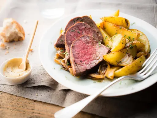 Tranches de roti de boeuf tendre, accompagnées de pommes de terre rôties et d'une sauce moutarde crémeuse.