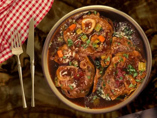 Un plat d'osso bucco mijoté, garni de persil frais, servi avec une serviette à carreaux rouges et blancs et des couverts.