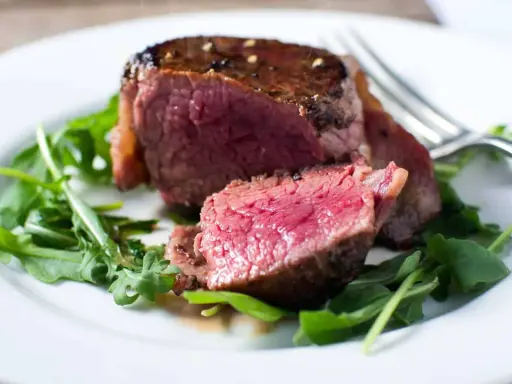 Un délicieux filet mignon, saignant et tendre, servi sur un lit de roquette fraîche.