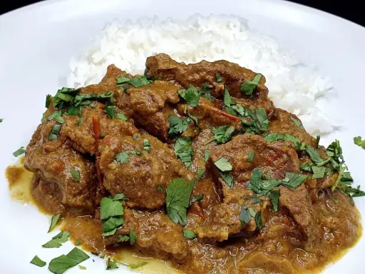 Un savoureux curry d'agneau, mijoté et garni de coriandre fraîche, servi avec du riz blanc.