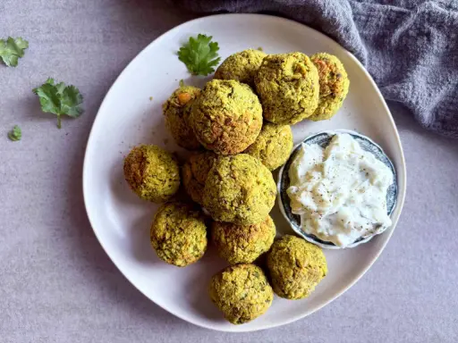 Assiette de falafels dorés, prêts à être dégustés. Une recette facile pour un plaisir garanti. Sauce blanche et coriandre pour accompagner.