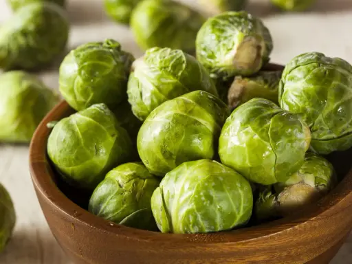 Un bol en bois rempli de choux de Bruxelles frais et verts. Ces petits légumes verts sont prêts à être cuisinés.