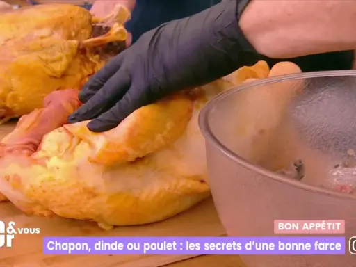 Main d'un cuisinier en gant noir préparant une farce poulet avec abats. Un chapon doré est à côté.