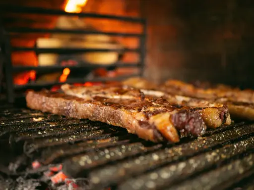 Bifteck grillé sur le feu, prêt à être servi avec une sauce piquante.