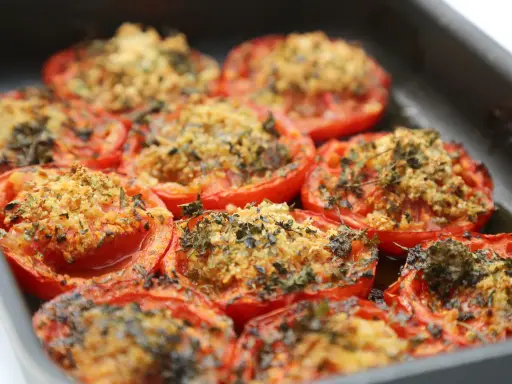 Tomates farcies au barbecue, gratinées et parsemées d'herbes fraîches, prêtes à être dégustées.