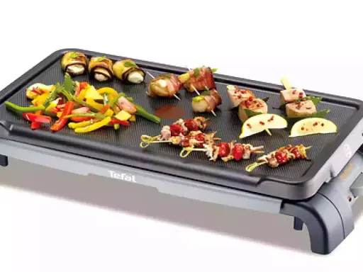 Brochettes de noix de Saint-Jacques et légumes colorés sur une plancha Tefal, prêts à être grillés pour un repas savoureux.