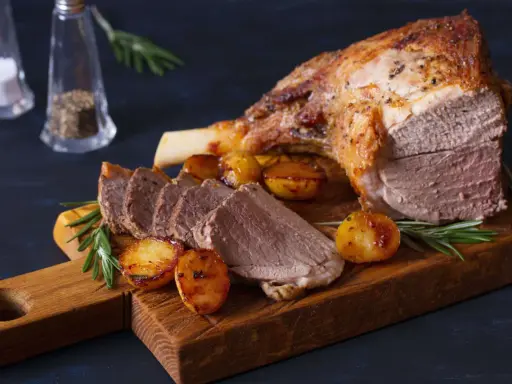 Gigot d'agneau rôti, pommes de terre et romarin sur une planche en bois. Un plat parfait pour la viande pour Pâques.