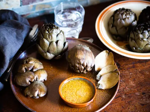 Artichauts prêts à être dégustés, accompagnés d'une sauce savoureuse. Une idée pour une recette artichaut simple et délicieuse.