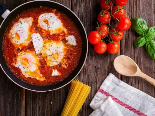 Œufs pochés dans une sauce tomate savoureuse, rappelant la sauce armoricaine, avec des tomates fraîches et du basilic.