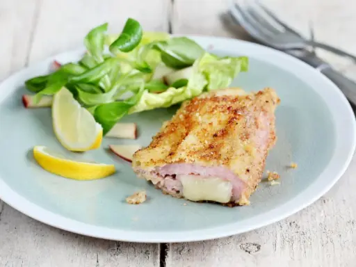 Un délicieux cordon bleu croustillant, garni de fromage fondant, servi avec une salade fraîche et des quartiers de citron.