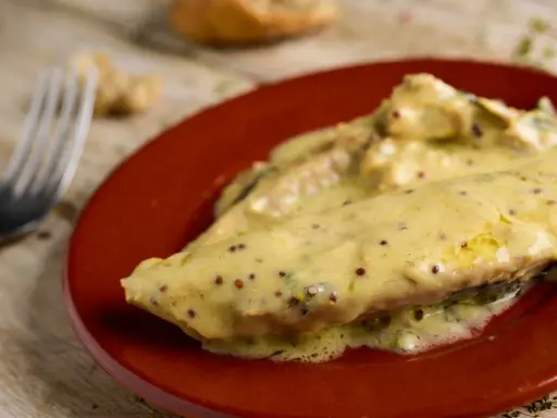 Poisson nappé d'une onctueuse sauce moutarde, servi sur une assiette rouge. Un délice !