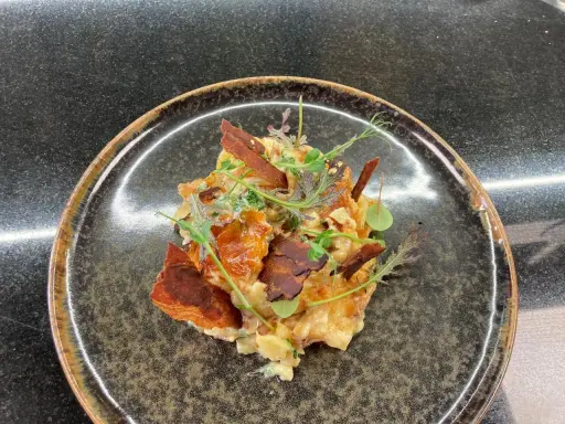 Une assiette de truffade recette, garnie de fines herbes et de lardons croustillants. Un plat réconfortant et savoureux.