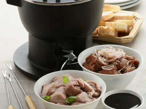 Préparation d'une fondue bourguignonne : viande blanche crue, viande cuite, pain et sauce. Des fourchettes à fondue sont prêtes.