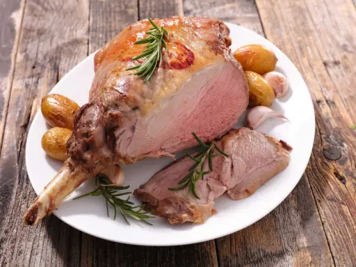 Gigot d'agneau rôti, tendre et juteux, accompagné de pommes de terre et d'ail. Un plat parfait pour un gigot pour 10 personnes.