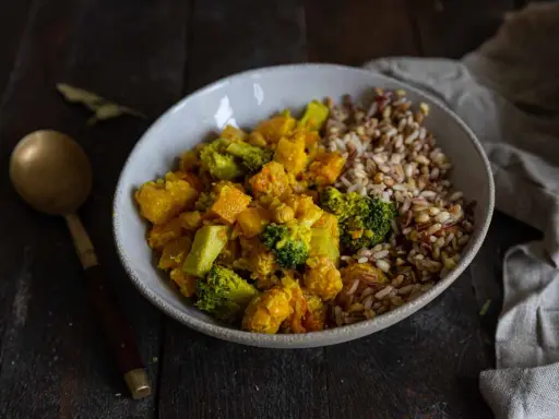 Un bol de riz et un curry de légumes coloré avec du brocoli, de la courge et des pois chiches.