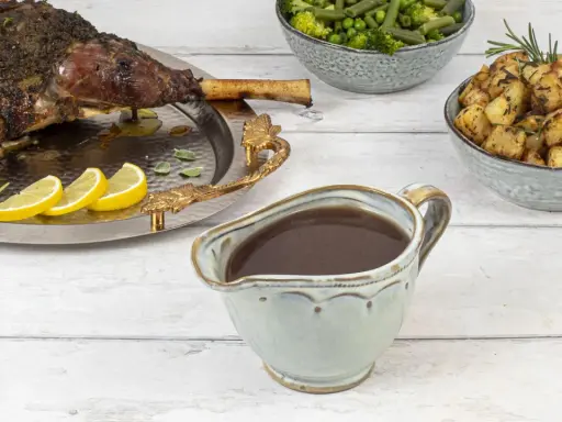 Sauce onctueuse pour accompagner une tranche de gigot d'agneau, avec des pommes de terre rôties et des légumes verts.