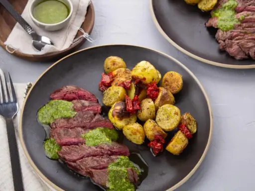 Tranches de bœuf juteux nappées de pesto, accompagnées de pommes de terre rôties et de tomates séchées. Quelle viande avec du pesto, un délice !