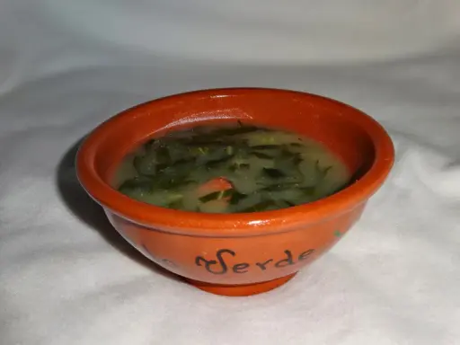Un bol en terre cuite orné du mot "Verde" contient un délicieux caldo verde, une soupe portugaise réconfortante aux légumes verts.
