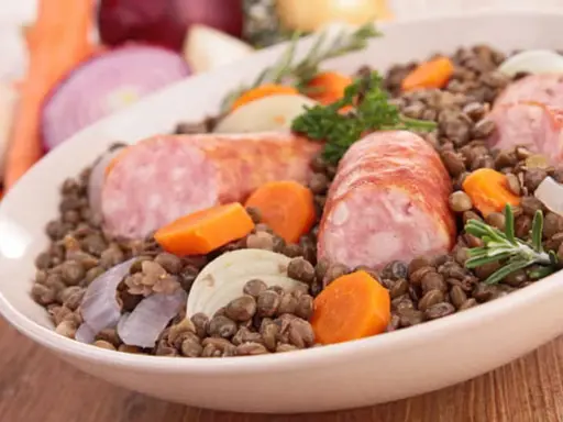 Un plat réconfortant de saucisses lentilles, garni de carottes, oignons et romarin.