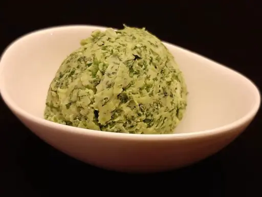 Une boule de beurre à l'ail et au persil dans un bol blanc. Parfait pour accompagner vos plats !