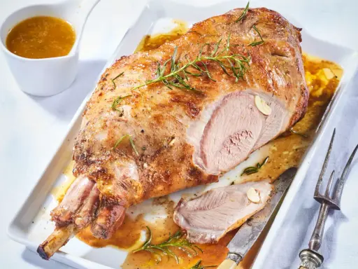 Gigot d'agneau pour 6 personnes, rôti à la perfection, servi avec sa sauce et garni de romarin.
