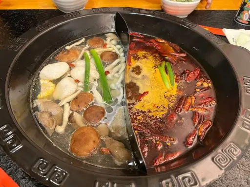 Une fondue chinoise à deux bouillons : un clair avec champignons et légumes, l'autre épicé aux piments.