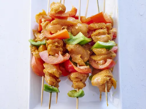 Brochettes de poulet marinées, tomates et poivrons verts, prêtes pour une recette brochette poulet barbecue.