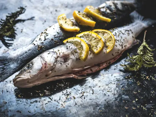 Deux poissons entiers, assaisonnés d'herbes et garnis de rondelles de citron, prêts pour un quel poisson barbecue.