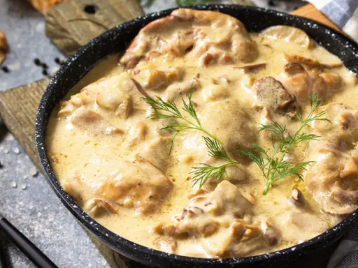 Poulet de Bresse à la crème, servi dans une poêle, garni d'aneth.