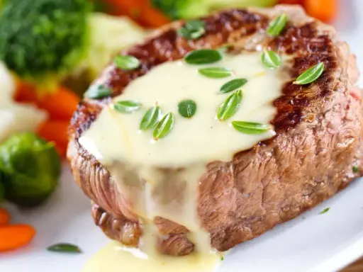Un steak tendre nappé d'une onctueuse sauce béarnaise, accompagné de légumes verts et de carottes.