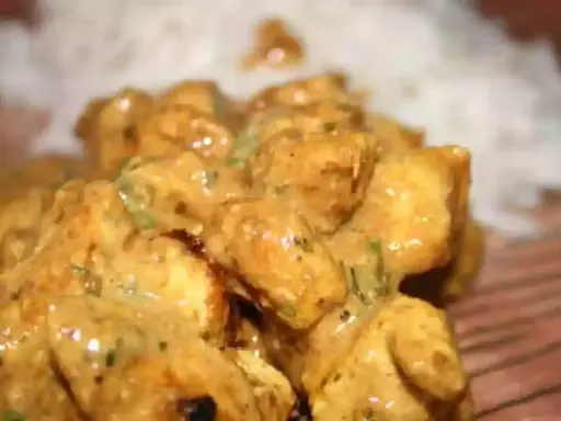 Délicieux poulet tikka en sauce crémeuse, servi avec du riz blanc. Un plat savoureux et réconfortant.