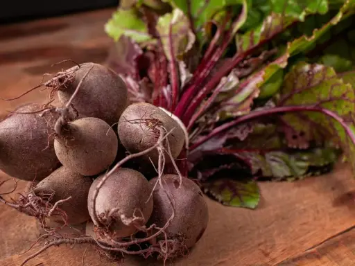 Un bouquet de betteraves fraîches, prêtes pour une délicieuse recette betterave. Leurs feuilles vertes et leurs racines pourpres promettent saveur et couleur.
