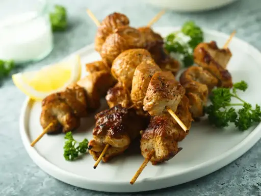 Brochettes de poulet citronnées, dorées et juteuses, garnies de persil frais et d'un quartier de citron. Un délice à savourer !