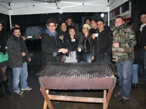 Un groupe d'amis profite d'un barbecue sous la pluie, sous un abri. L'ambiance est conviviale malgré les gouttes.