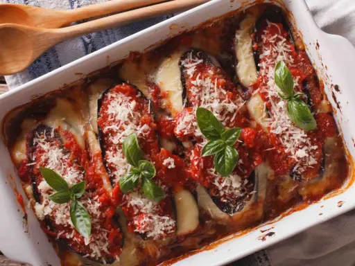 Aubergine parmigiana gratinée, garnie de sauce tomate, fromage fondant et basilic frais. Un délice italien prêt à être dégusté.