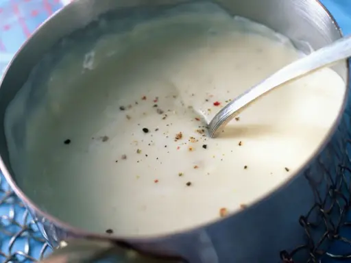 Sauce béchamel sans beurre, onctueuse et parsemée de poivre, prête à être dégustée.