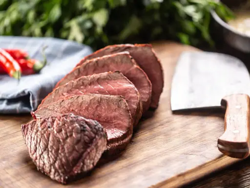 Tranches de rôti de bœuf, poivrons rouges et couteau de boucher. Que faire avec ce reste de viande cuite ?