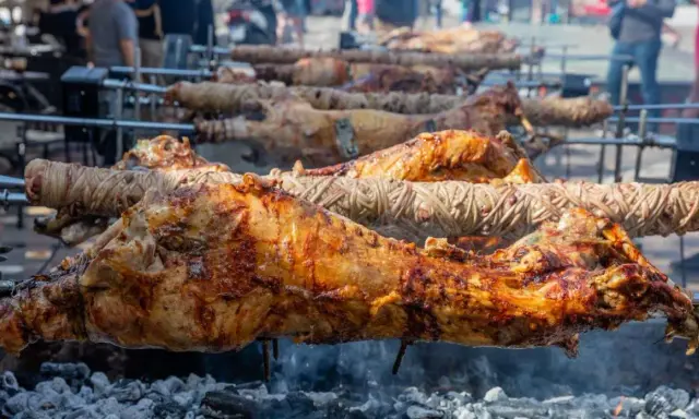 Plusieurs agneaux à la broche rôtissent lentement sur des feux de bois. La peau dorée et croustillante promet un délice savoureux.