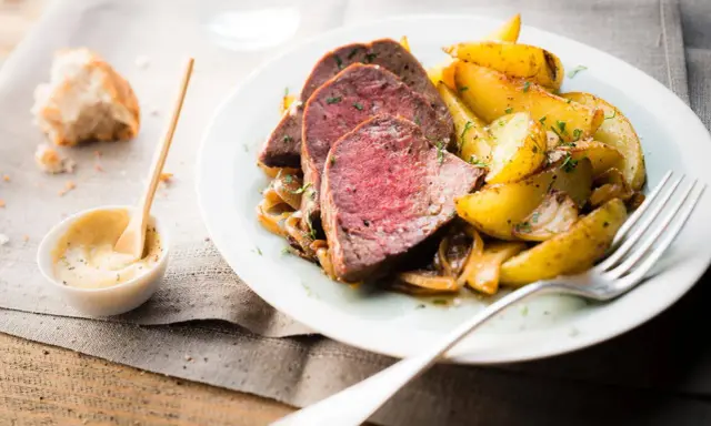 Tranches de roti de boeuf tendre, accompagnées de pommes de terre rôties et d'une sauce moutarde crémeuse.
