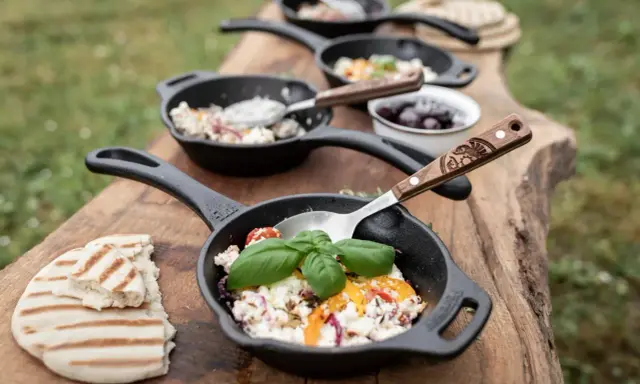 Petits woks de fromage frais, tomates et herbes, servis sur une planche en bois avec du pain grillé. Parfait pour un bbq.