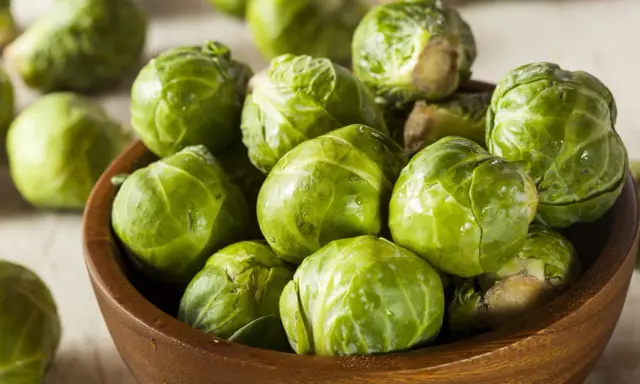 Un bol en bois rempli de choux de Bruxelles frais et verts. Ces petits légumes verts sont prêts à être cuisinés.