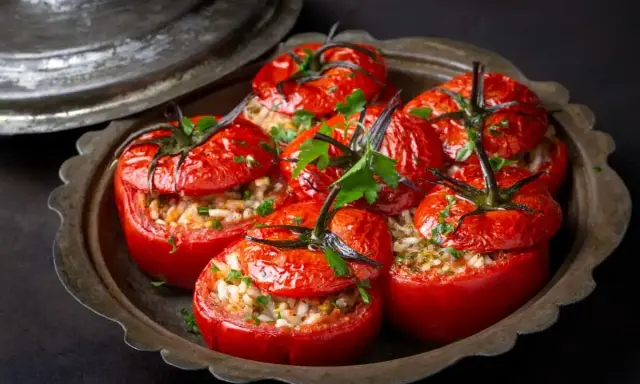 Tomates farcies au riz au four, garnies de persil frais, servies dans un plat en métal patiné. Un délice simple et savoureux.