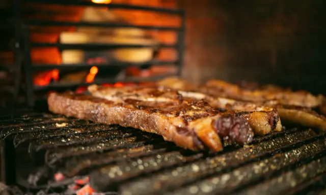 Bifteck grillé sur le feu, prêt à être servi avec une sauce piquante.