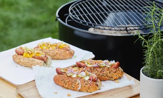 Délicieux hot dogs prêts pour un barbecue, avec des garnitures fraîches et un pain aux graines.