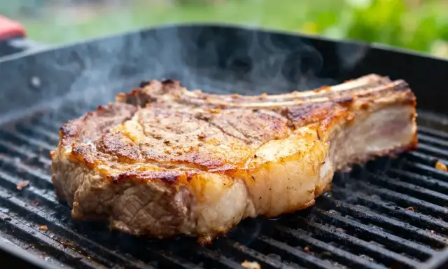 Un gros morceau de bœuf sur un gril, fumant doucement. La cuisson lente au barbecue révèle une croûte dorée et une chair juteuse.