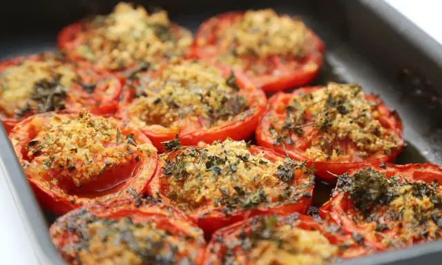 Tomates farcies au barbecue, gratinées et parsemées d'herbes fraîches, prêtes à être dégustées.